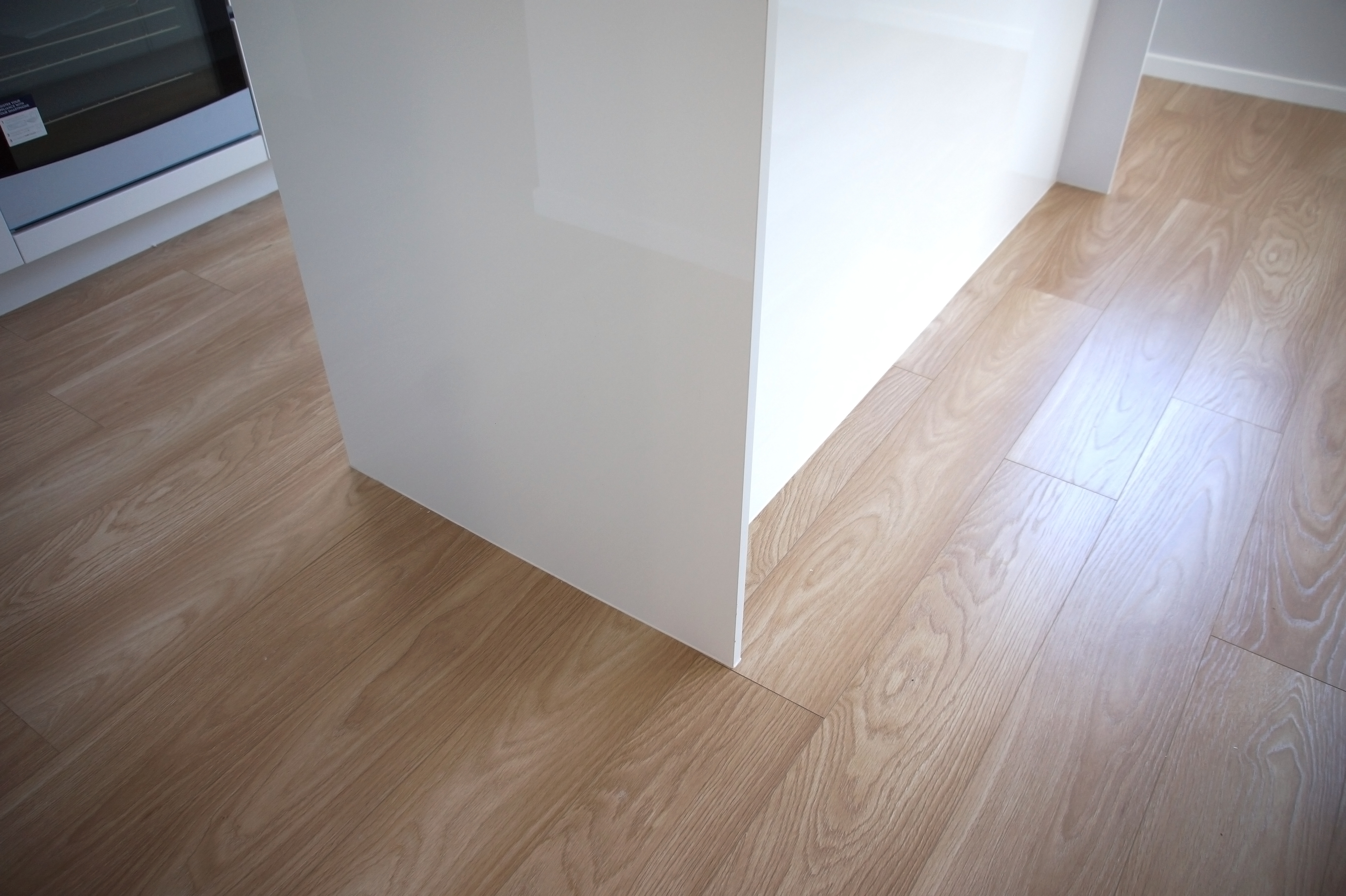 Close-up of laminate flooring joins beside kitchen island cabinetry