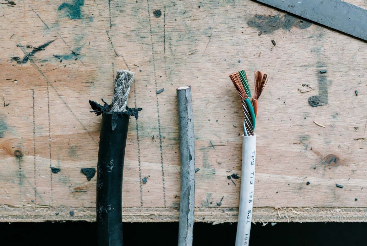 Cut ends of old and new house wiring cable compared on workbench